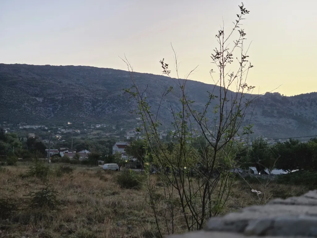 Landschaft mit Blick auf ein Dorf und einen Berg im Abendlicht.